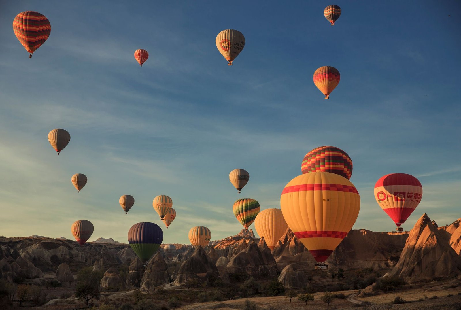 Colourful hot air balloons rising at sunrise over the fairy chimney rock formations of Cappadocia in Turkey