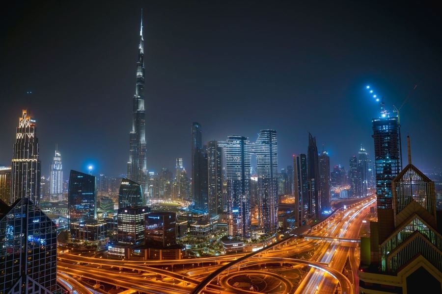 Downtown Dubai skyline at night with the Burj Khalifa lit up and light trails on the highway below