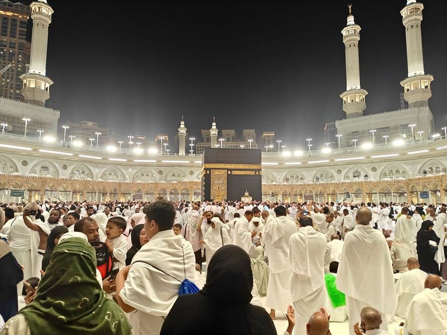 Pilgrims in white ihram circling the Kaaba at Masjid al-Haram in Makkah at night